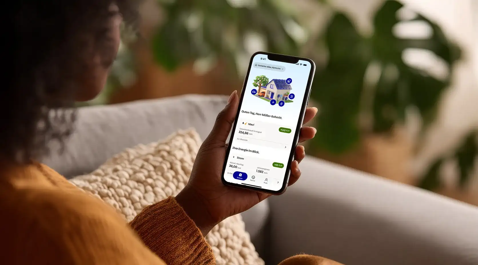 Frau hält Smartphone in der Hand mit der Startseite der EnBW zuhause+ App