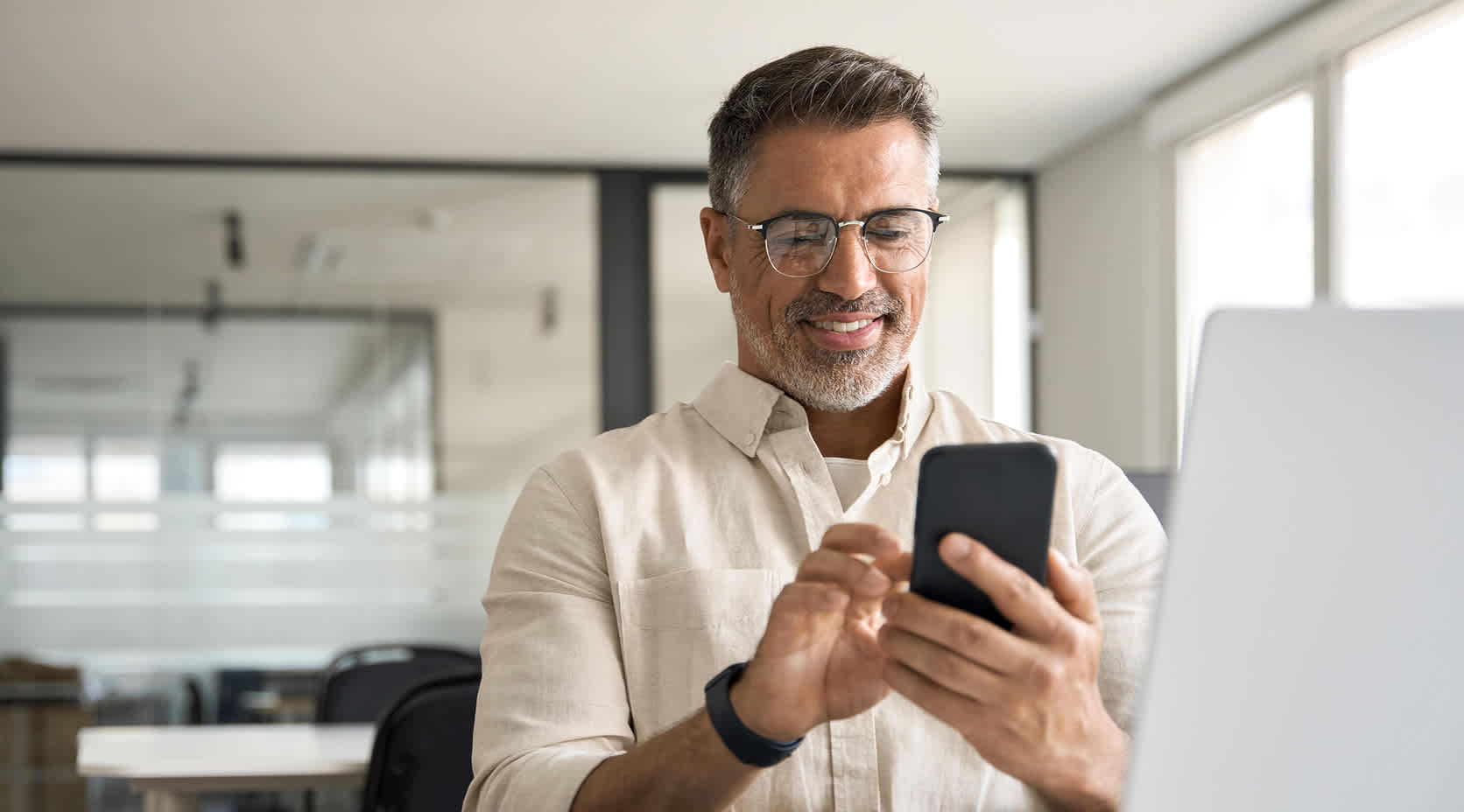 Mann mit Smartphone in seinem Büro.
