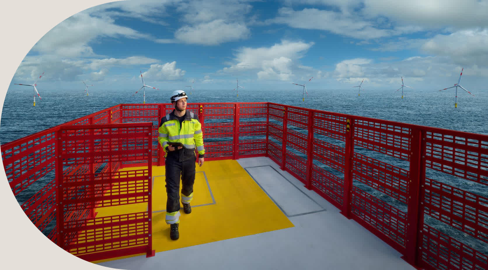 Ein Arbeiter auf einem Offshore Windpark mit Windrädern im Hintergrund.