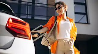Frau mit Sonnenbrille lädt das Auto