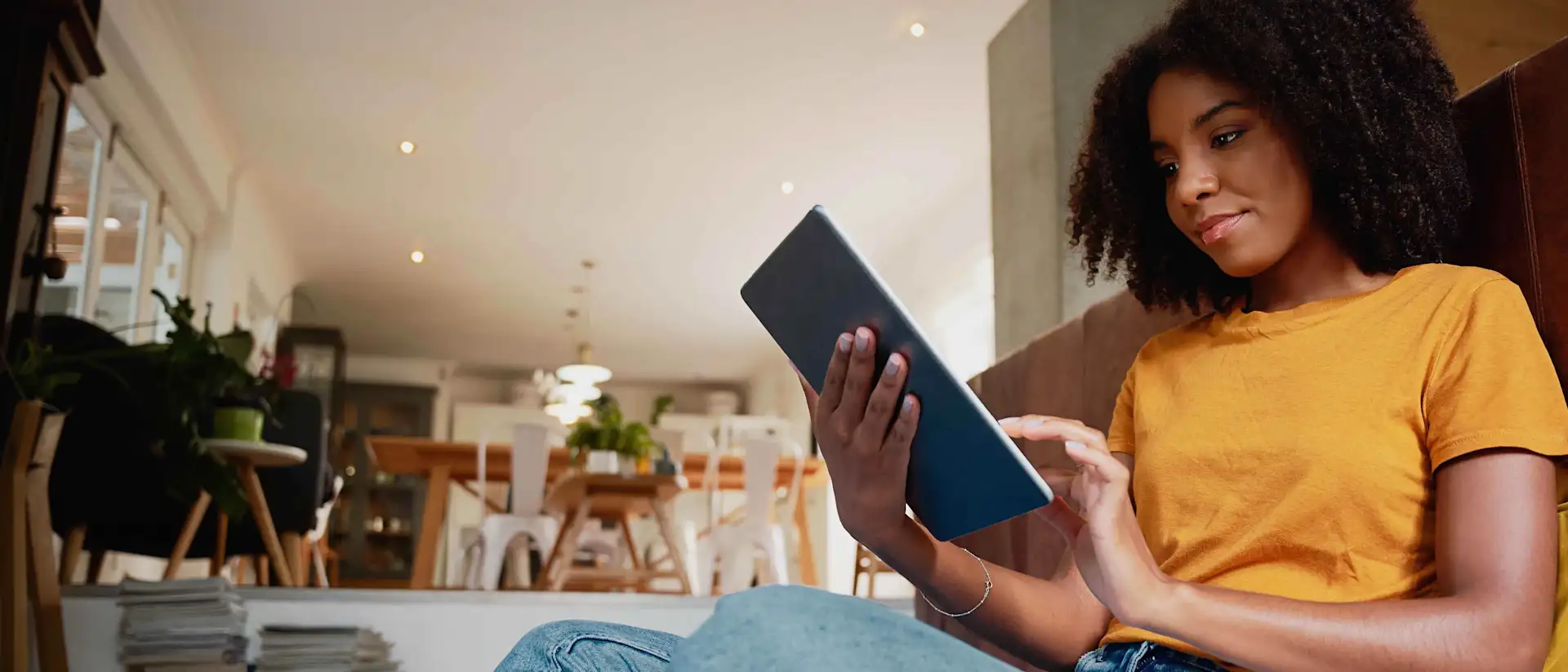 Frau mit Locken und orangenem T-Shirt hält Tablet