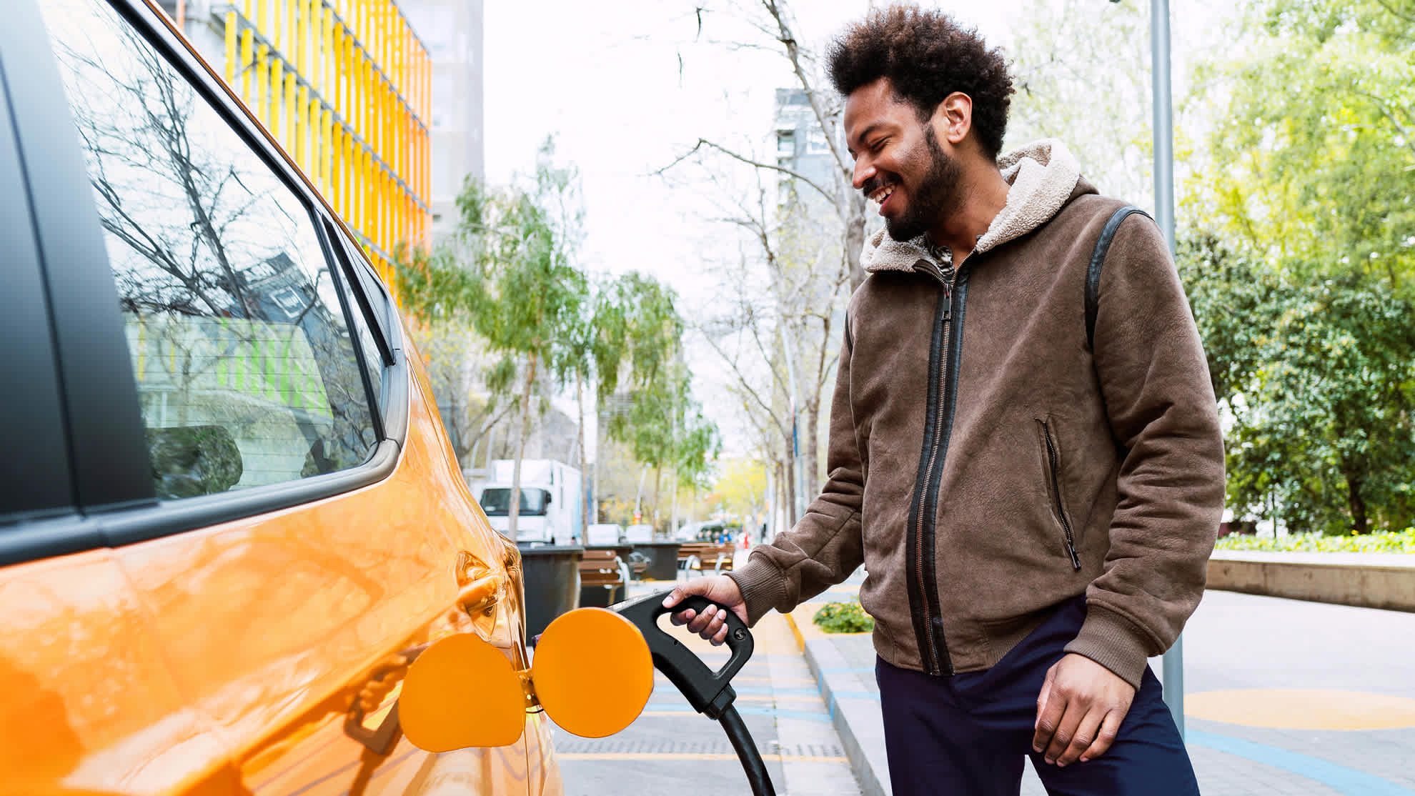 Mann lädt Auto an E-Ladesäule