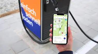 Mensch bezahlt mit mobility+ App vor einer Ladesäule