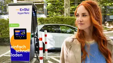 Rothaarige Frau vor EnBW-Ladesäule