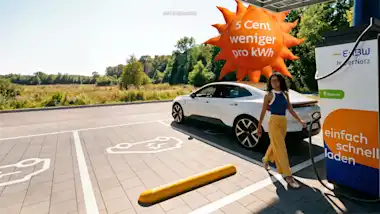 Frau lädt Ihr E-Auto an einer EnBW-Ladesäule an einem Ladepark, neben ihr fliegt ein großer Luftballon in Form einer Sonne mit der Aufschrift "5 Cent weniger pro kWh"