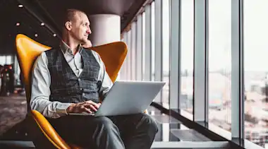 Mann mit Notebook schaut aus dem Fenster