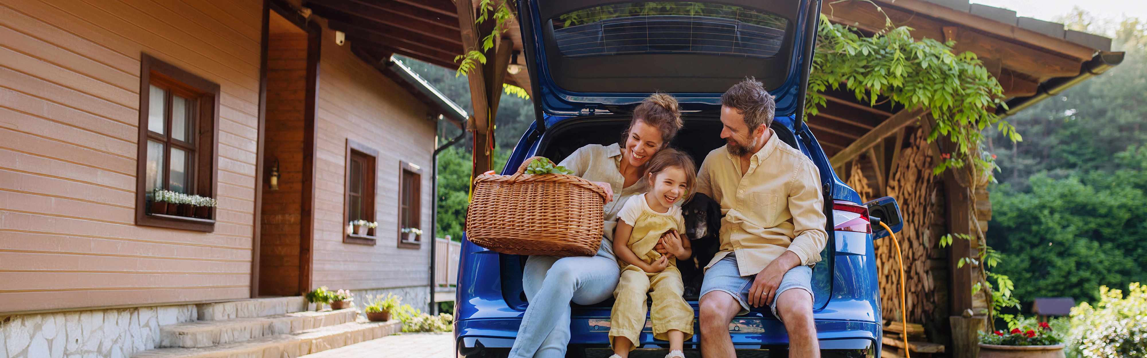 EnBW Familie sitzt freudig im Kofferraum eines Autos