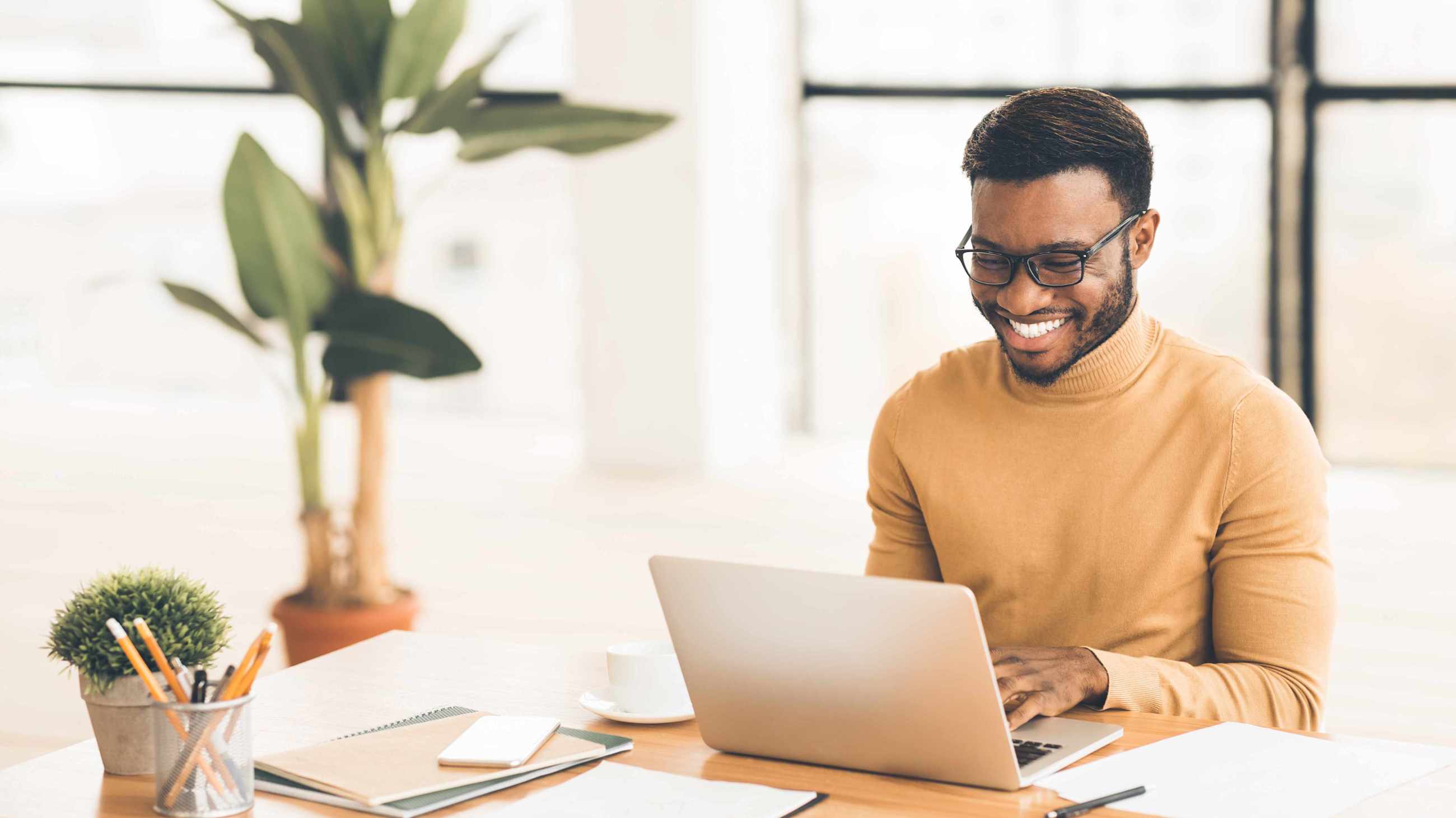 Junger Mann arbeitet lächelnd an Notebook