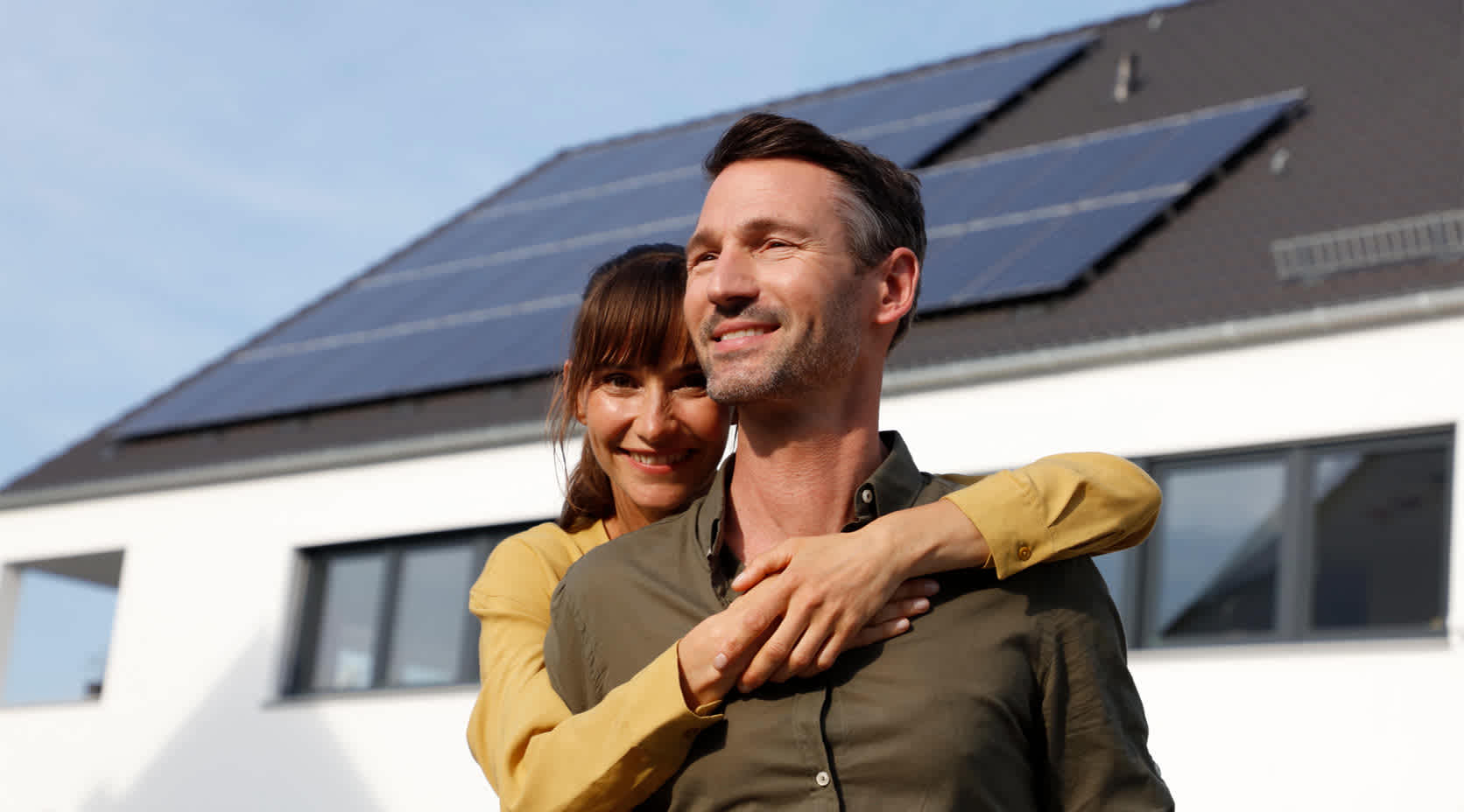 Paar vor Haus mit Solaranlage