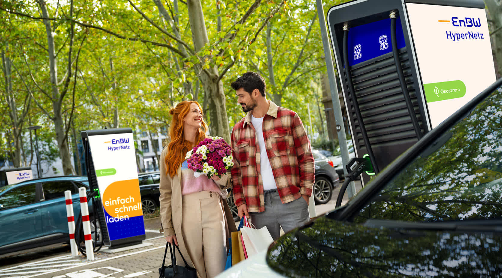 Partner mit Blumen vor Ladestation