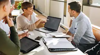 Meeting mit 4 Personen, Junge Frau am Laptop