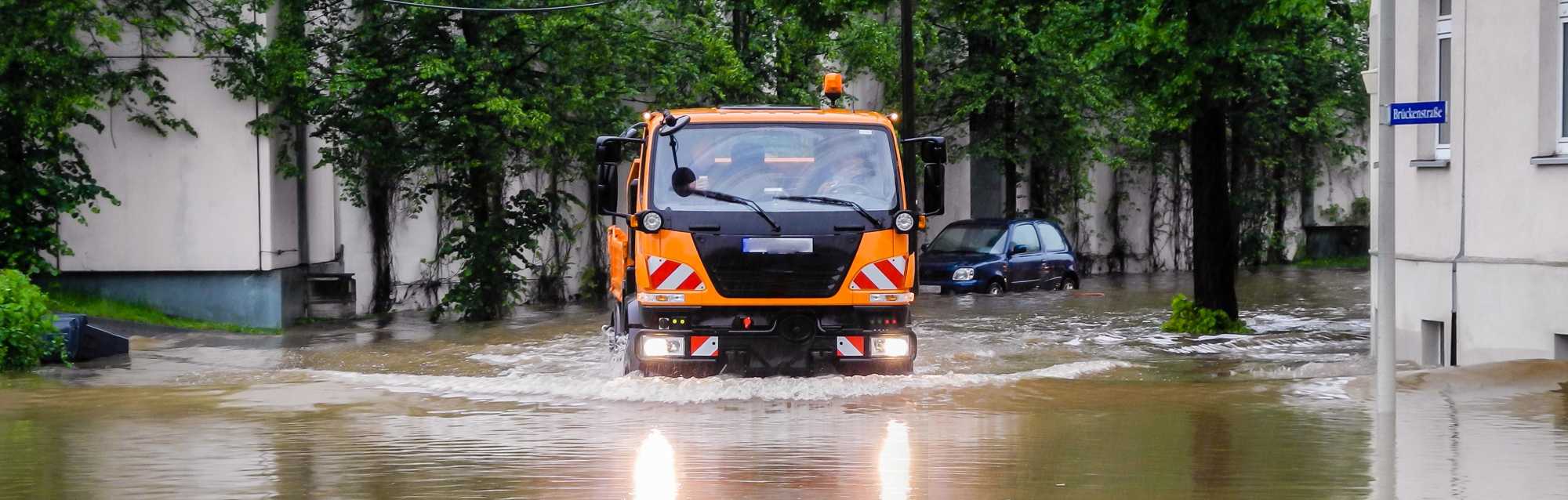 Kommunaler LKW fährt durch ein Hochwassergebiet