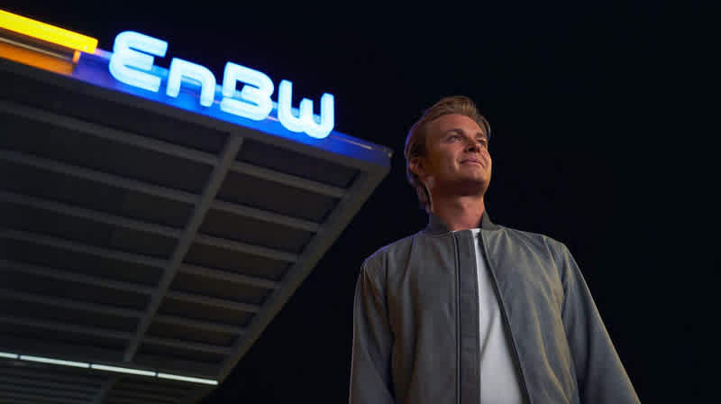 Nico Rosberg vor EnBW Logo an EnBW Ladepark bei Nacht