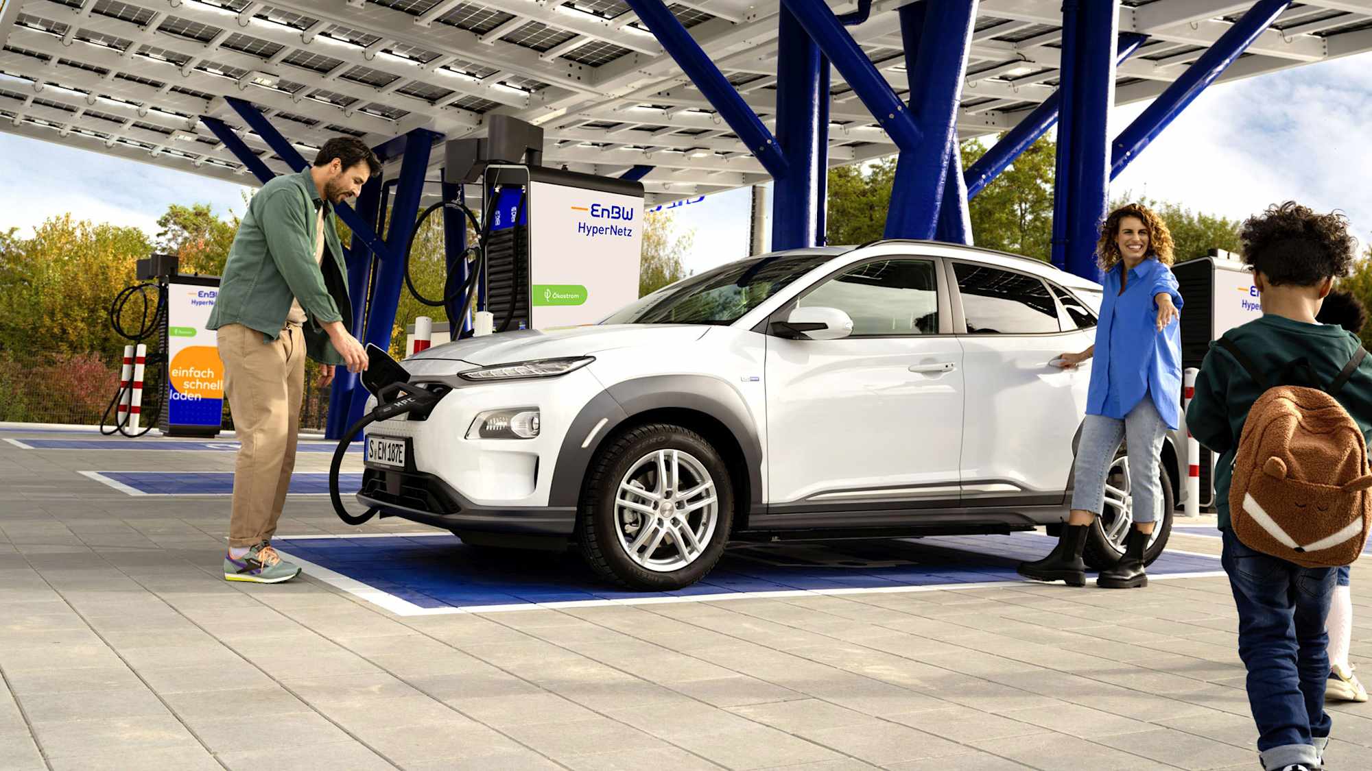 Paar mit Kind lädt E-Auto