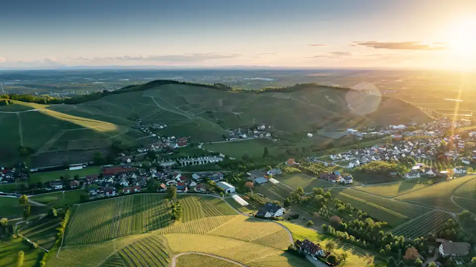 Blick Vogelperspektive auf Dorf mit vielen Feldern und strahlender Sonne