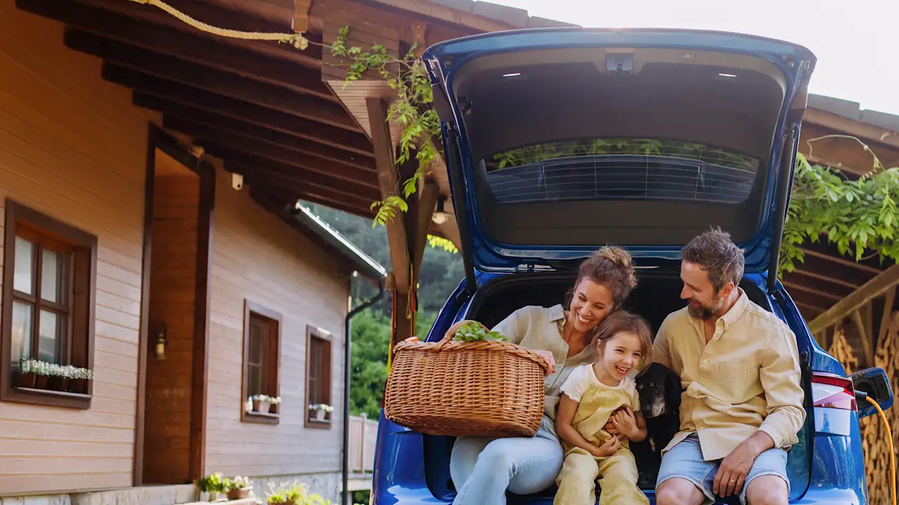 Familie sitzt freudig im Kofferraum eines Autos