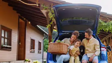 Familie sitzt freudig im Kofferraum eines Autos