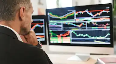 Geschäftsmann blickt auf Bildschirm mit Charts