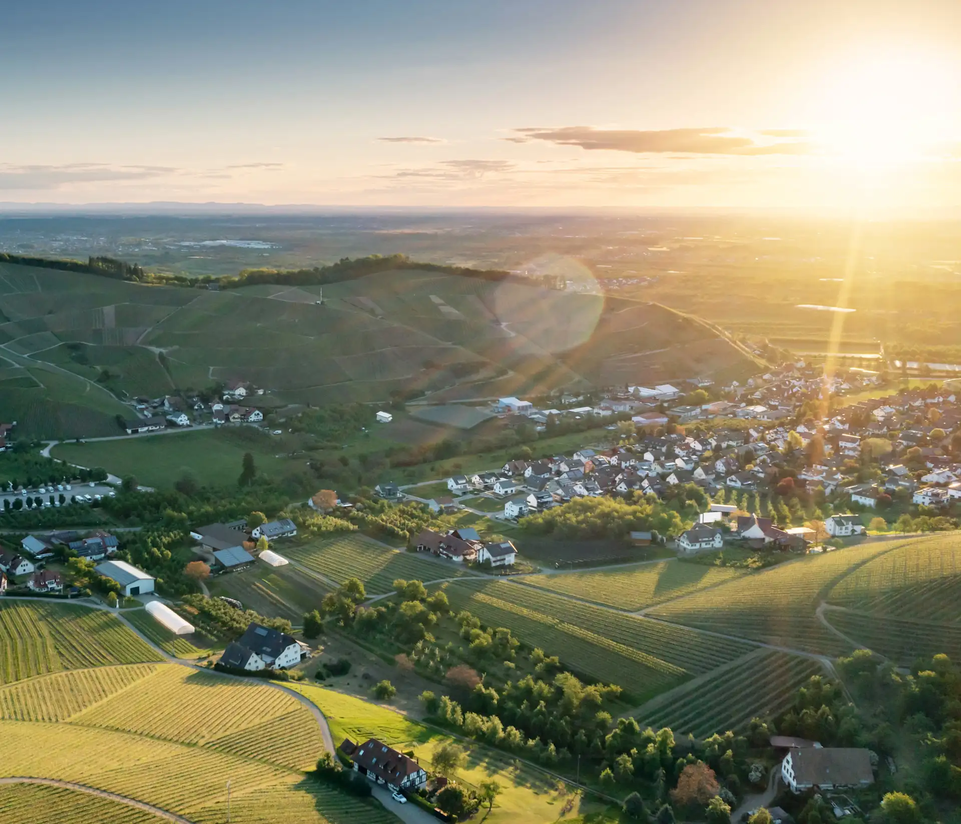 Blick Vogelperspektive auf Dorf mit vielen Feldern und strahlender Sonne