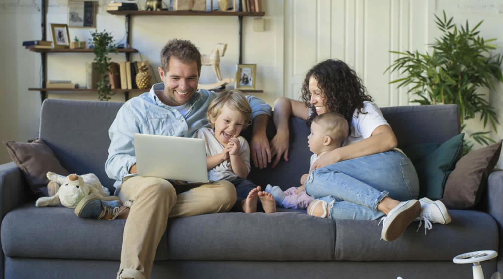 Familie mit Kind und Baby sitzt auf Sofa.