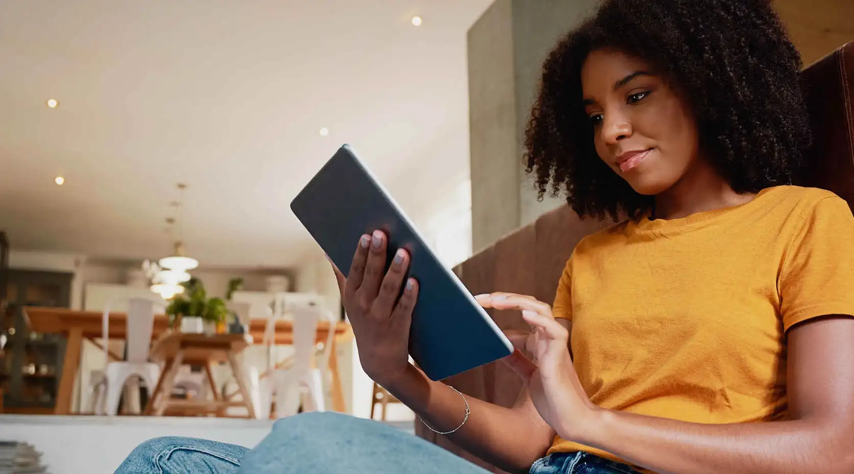 Frau mit Locken und orangenem T-Shirt hält Tablet