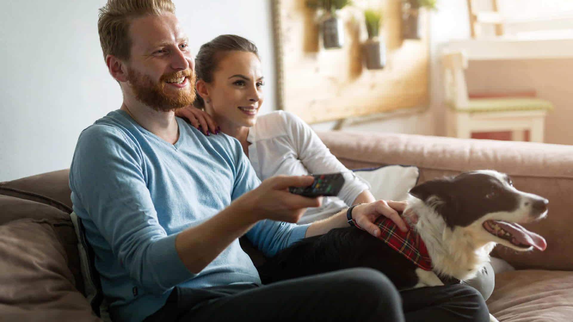 Pärchen auf der Couch erleben Fernsehen mit EnBW Entertain+