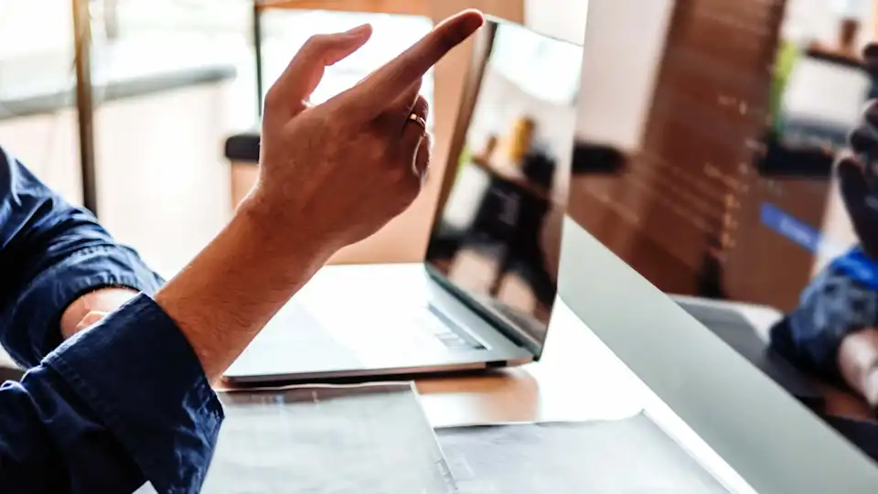 Mann zeigt mit Finger auf Monitor