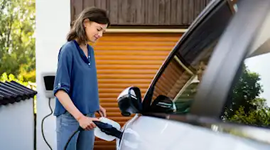 Frau lädt an heimischer Wallbox