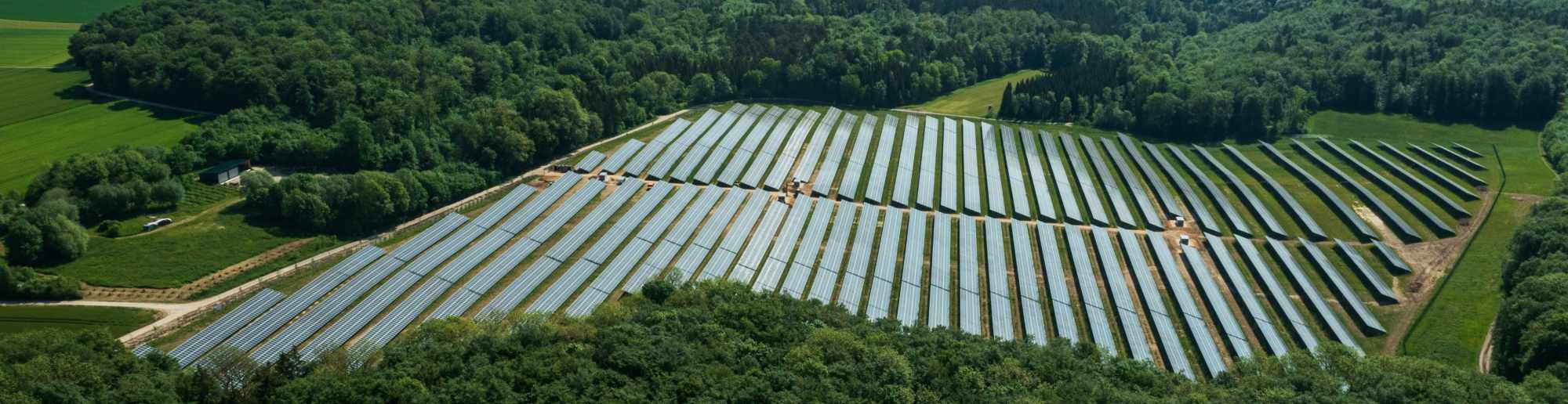 Solarpark umgeben von Feld und Wald aus der Vogelperspektive