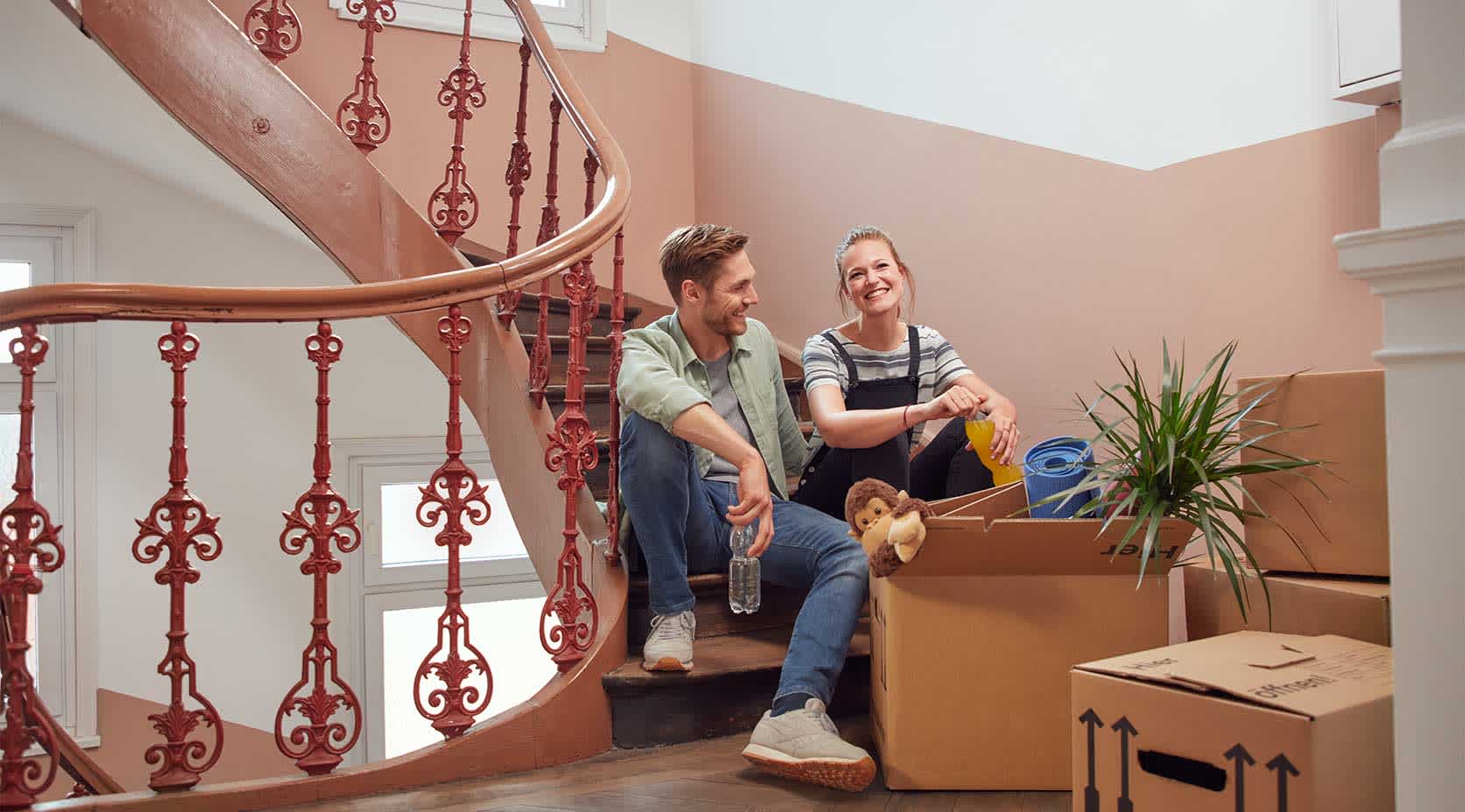 Junges Paar sitzt mit Umzugskartons auf Treppe