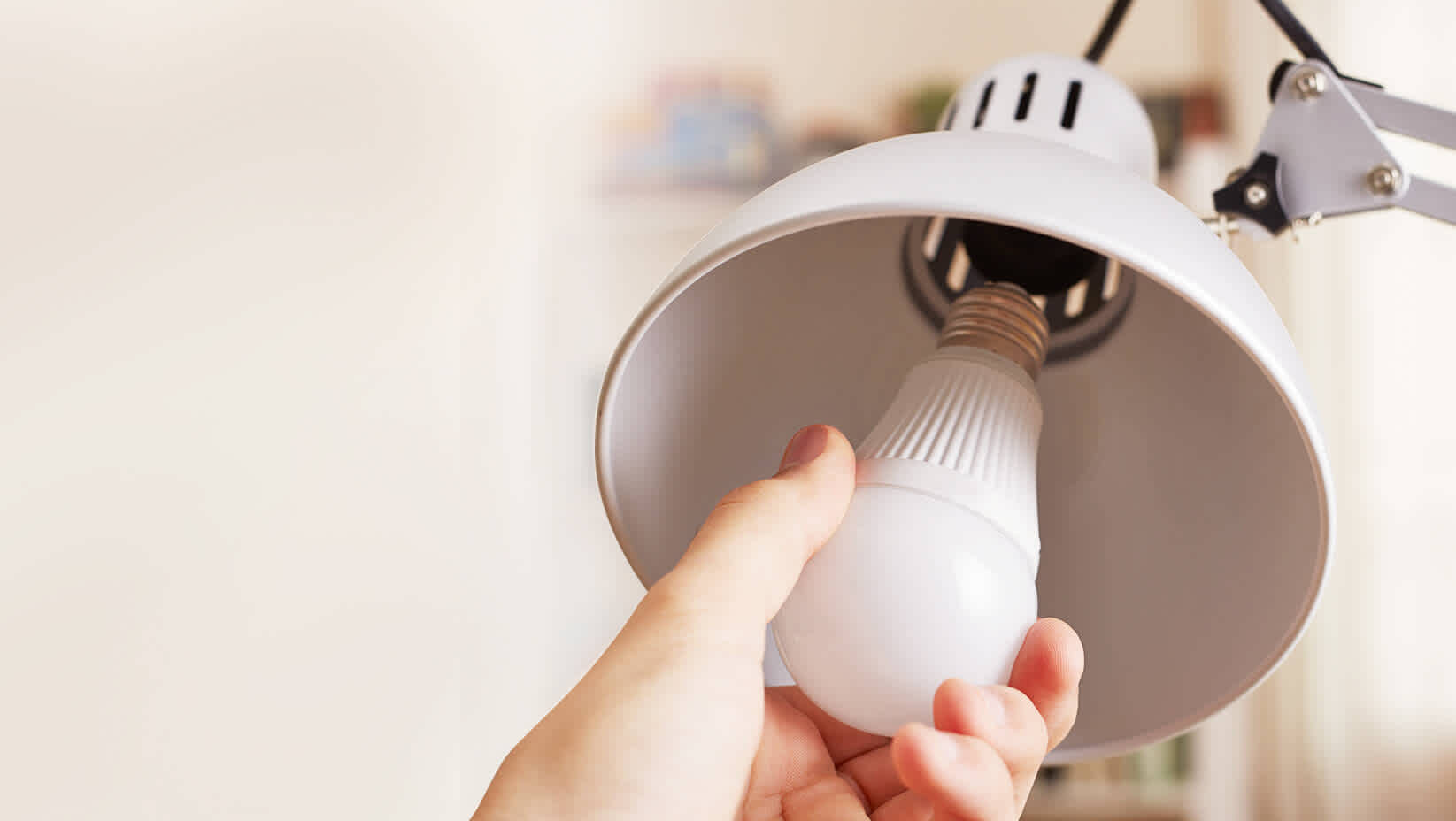 Hand dreht energiesparendes Leuchtmittel in Lampe