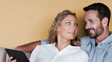 Mann und Frau schauen auf ein Tablet.