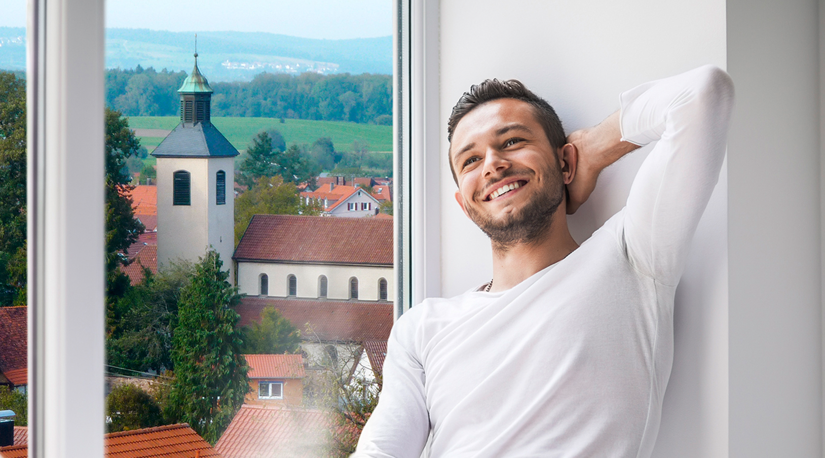 Mann sitzt auf der Fensterbank mit Aussicht auf Bad Boll