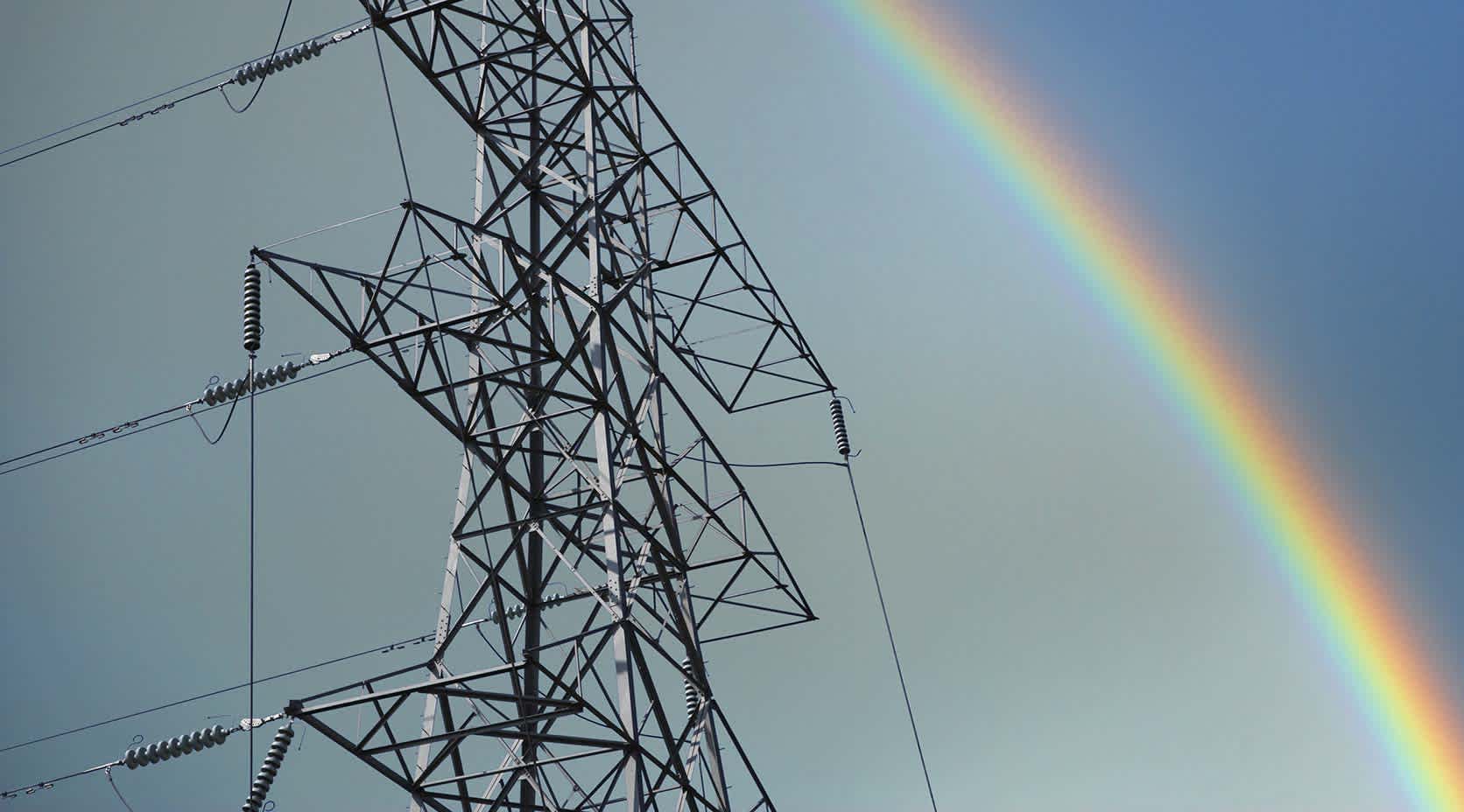 Strommast mit Regenbogen im Hintergrund