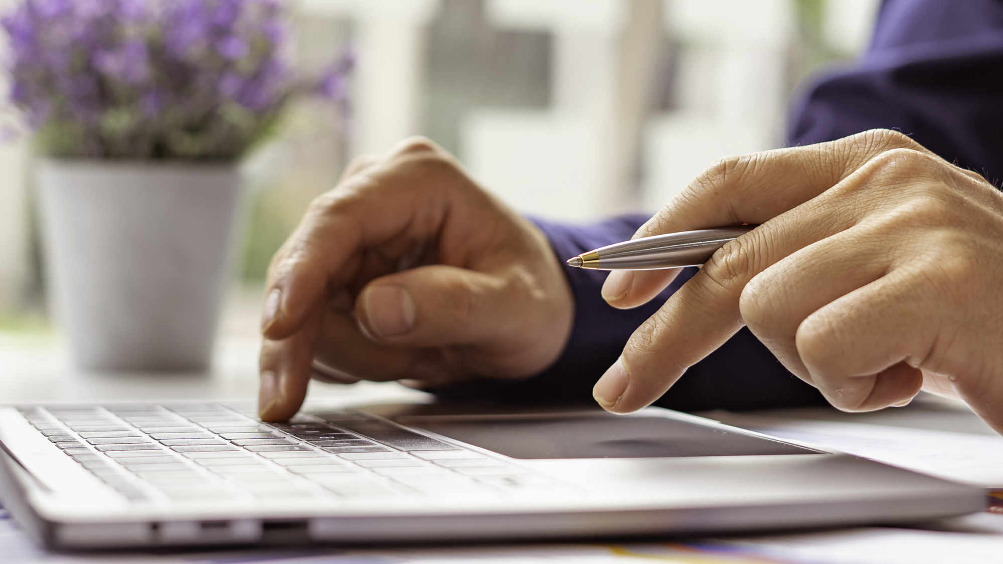 Mann mit Stift in der Hand arbeitet an einem Notebook