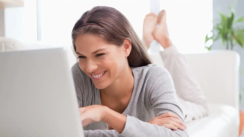 Frau arbeitet auf der Couch mit einem Notebook