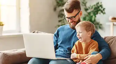 Vater und Kind am Laptop suchen günstigen Stromanbieter