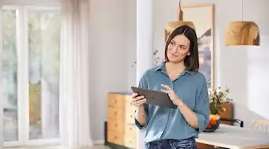 Frau nutzt Tablet zur Steuerung ihres Smart-Homes