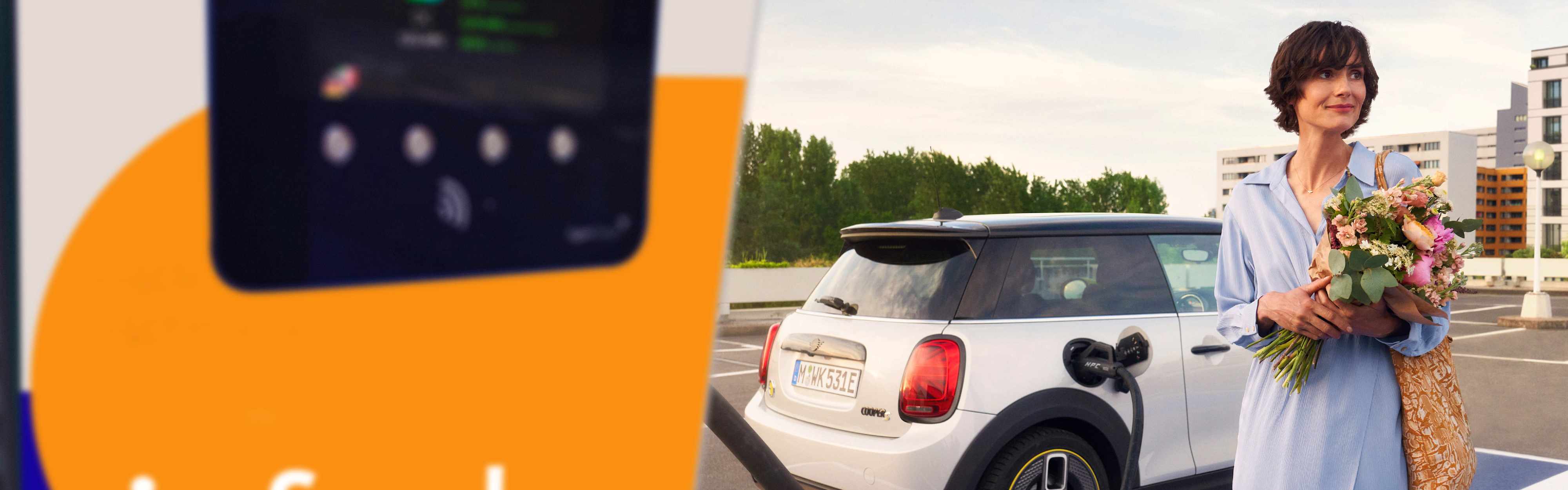 Frau auf Parkplatz lädt E-Auto nach Einkauf