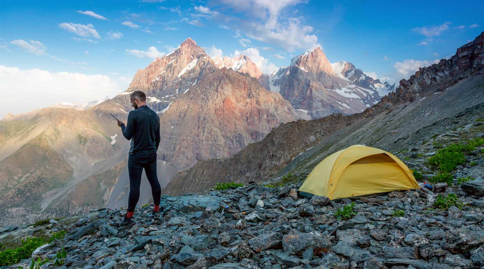 Bergsteiger mit Telefon steht auf einem Gipfel