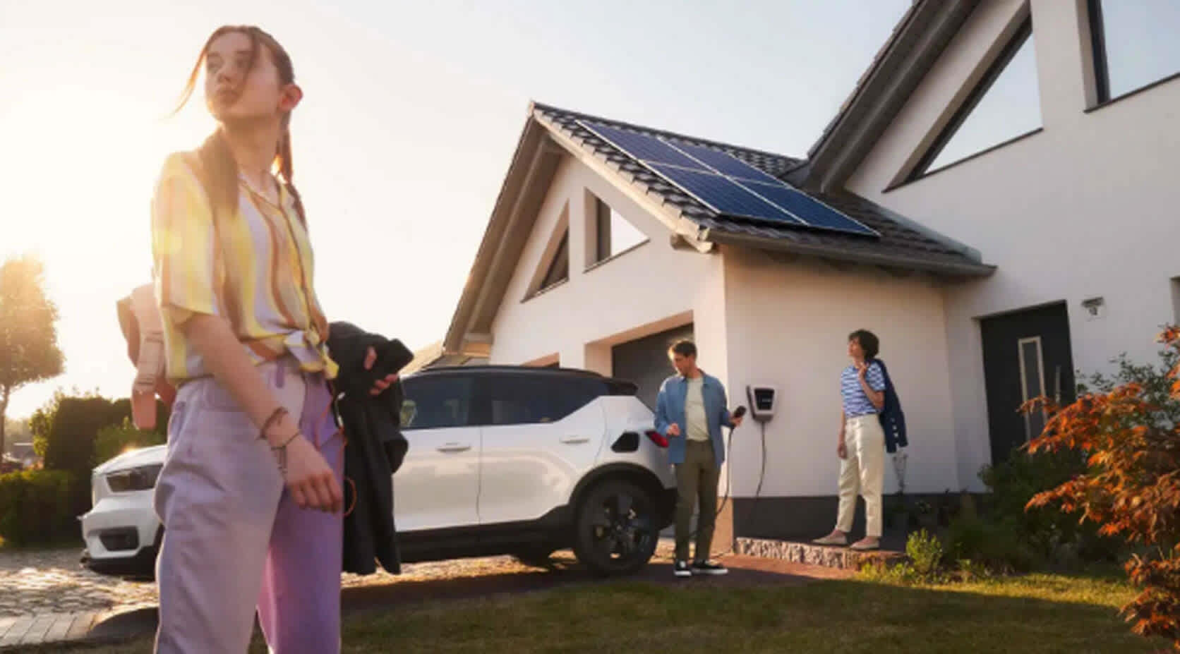 Familie mit Elektroauto vor einem Haus