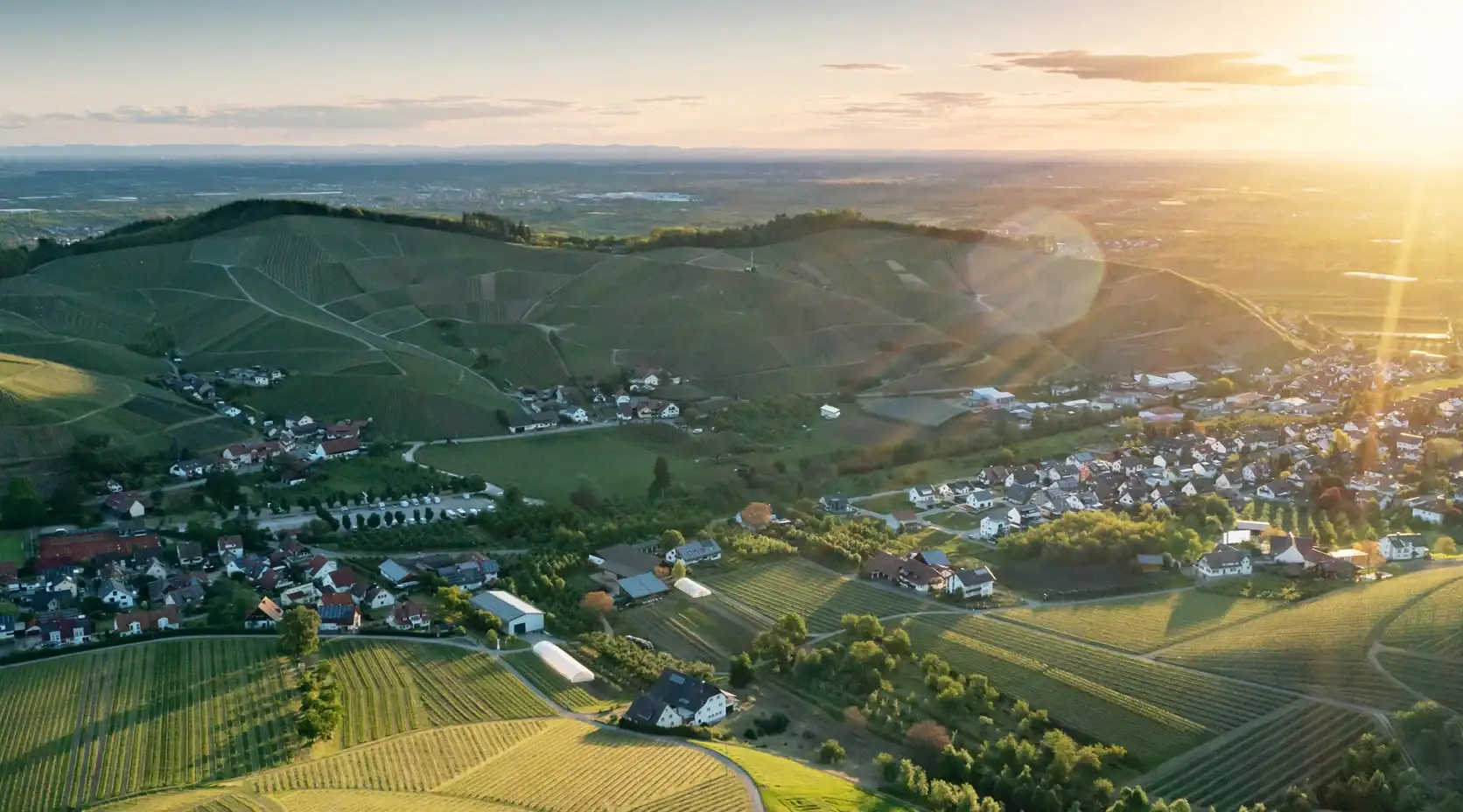 Blick Vogelperspektive auf Dorf mit vielen Feldern und strahlender Sonne