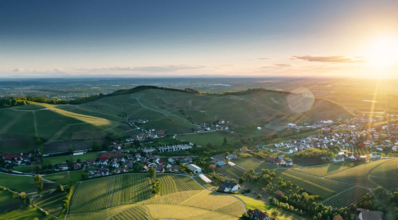 Blick Vogelperspektive auf Dorf mit vielen Feldern und strahlender Sonne