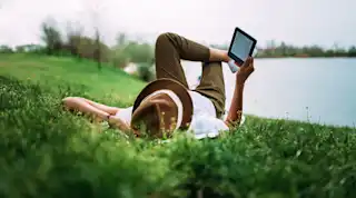 Frau liest E-Book am See