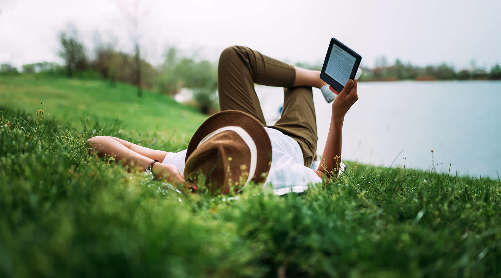 Frau liest E-Book am See