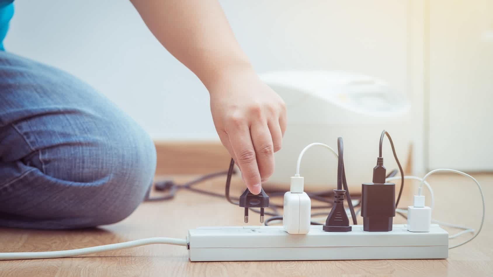 Hand steckt Stecker in Steckdosenleiste