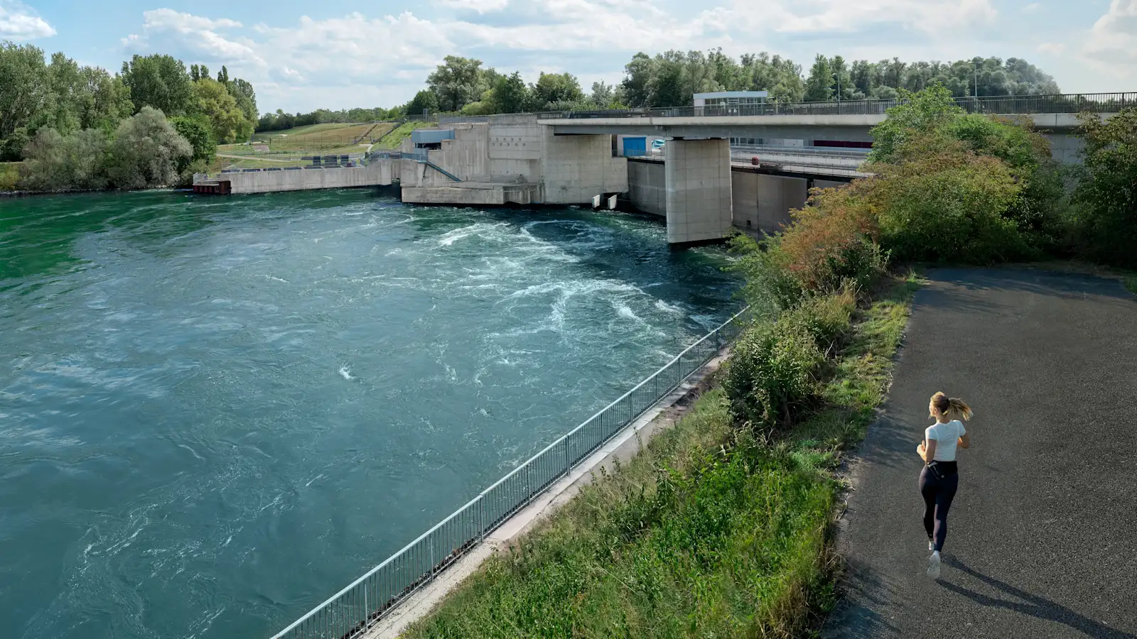 Joggerin läuft am Wasserkraftwerk vorbei