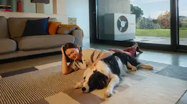 Kurzhaarige braunhaarige Frau liegt mit Hund auf Teppich