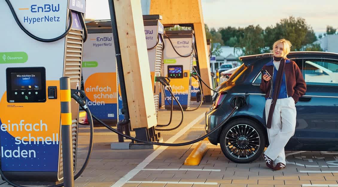 Junge Frau mit Smartphone in einem EnBW Ladepark