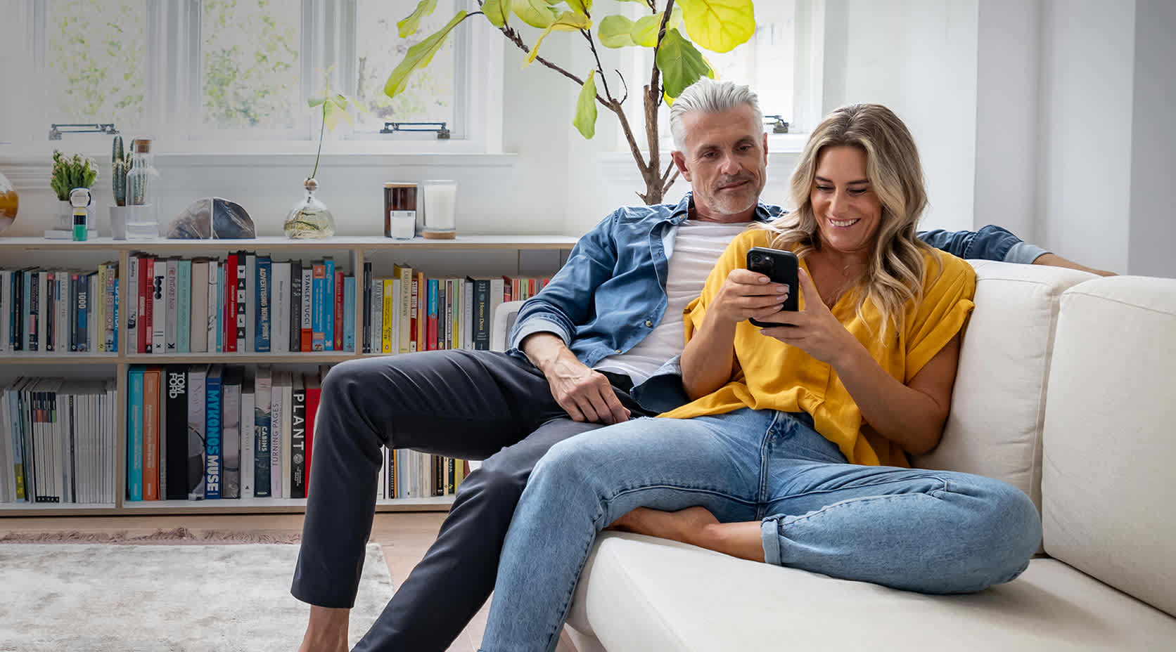 Erwachsenes Paar sitzt auf der Couch und schaut aufs iPad